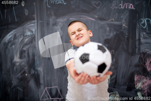 Image of happy boy holding a soccer ball in front of chalkboard