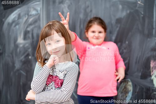 Image of little girls having fun in front of chalkboard