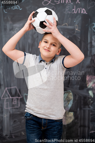 Image of happy boy holding a soccer ball on his head