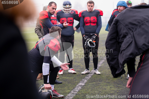 Image of american football player discussing strategy with his team