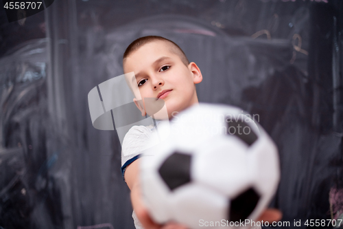 Image of happy boy holding a soccer ball in front of chalkboard