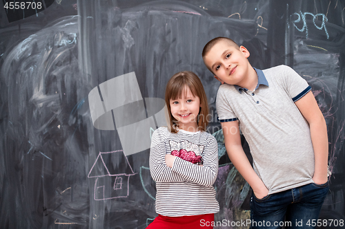 Image of boy and little girl standing in front of chalkboard