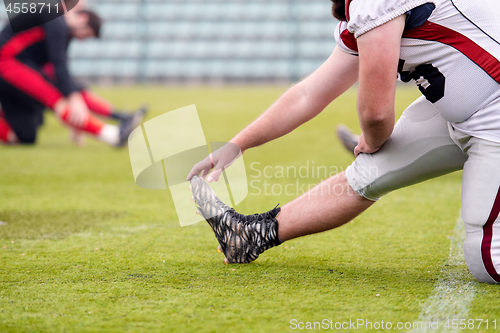 Image of american football players stretching and warming up