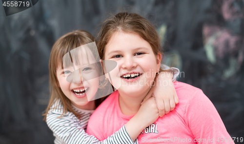 Image of little girls hugging in front of chalkboard