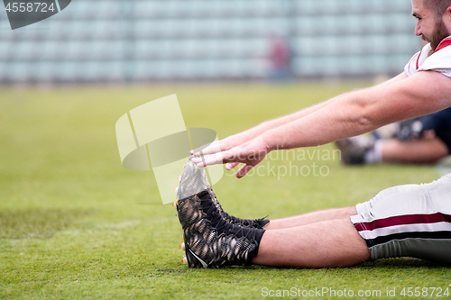 Image of american football players stretching and warming up