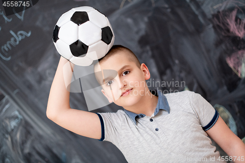 Image of happy boy holding a soccer ball on his head