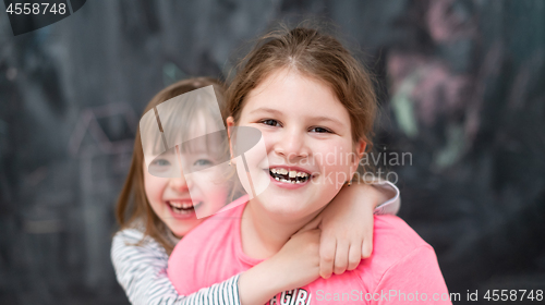 Image of little girls hugging in front of chalkboard