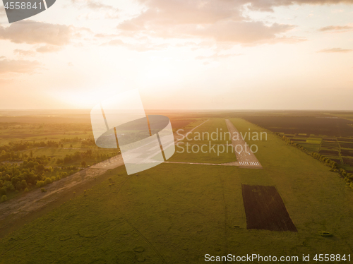 Image of Aerial view from the drone, a bird\'s eye view of abstract geometric forms of abandoned runway, forests and fields in the summer evening at sunset.