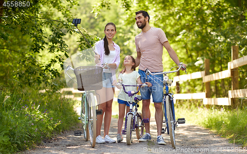 Image of happy family with bicycles taking selfie in summer