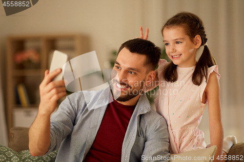 Image of father and daughter taking selfie at home