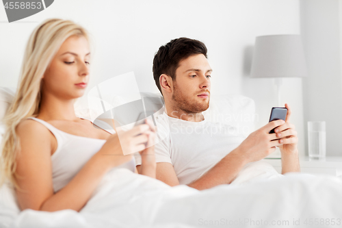 Image of couple with smartphones in bed