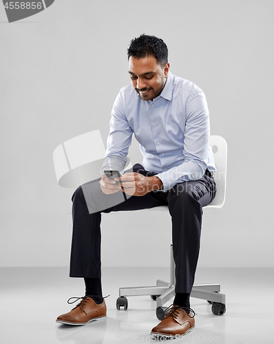 Image of smiling indian businessman sitting on office chair