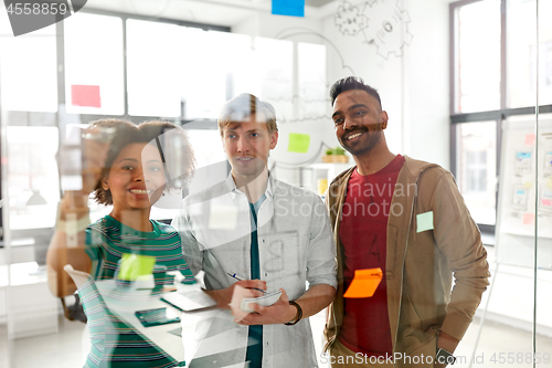 Image of happy creative team at office glass board