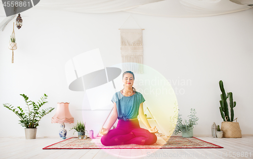 Image of woman meditating in lotus pose at yoga studio