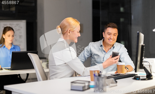 Image of business people with smartphone at night office