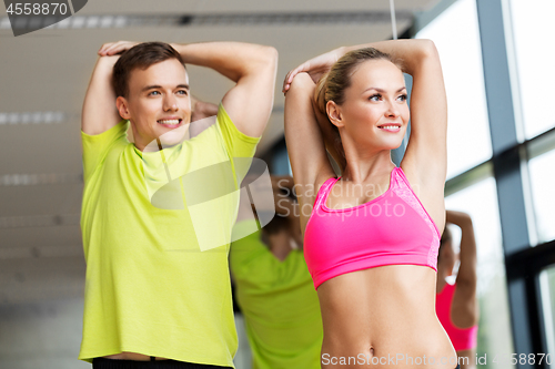 Image of smiling man and woman exercising in gym