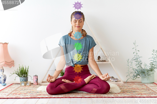 Image of woman meditating in lotus pose at yoga studio