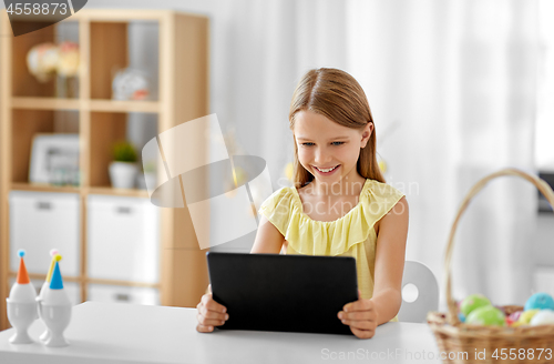 Image of happy girl with tablet pc and easter eggs at home