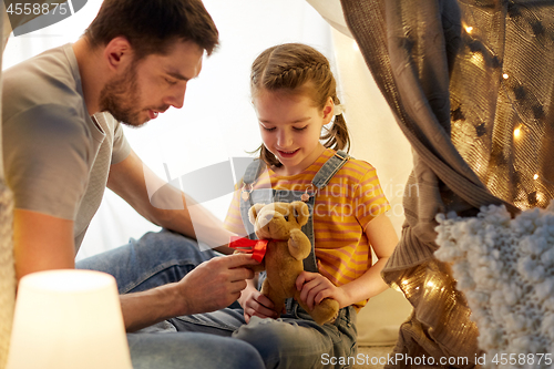 Image of happy family playing with toy in kids tent at home