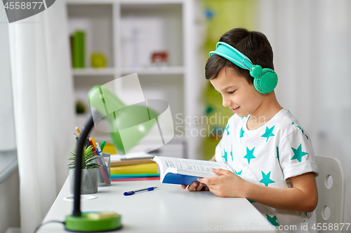 Image of boy in headphones with textbook learning at home