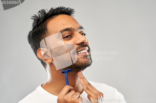 Image of indian man shaving beard with razor blade