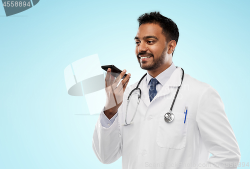 Image of smiling indian male doctor calling on smartphone