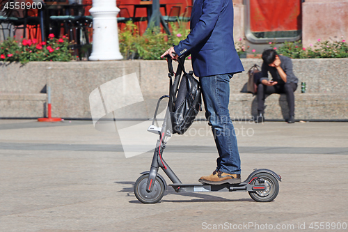 Image of Man riding a kick scooter at the city square