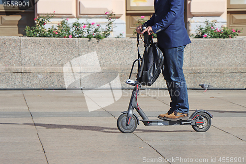 Image of Man riding a kick scooter at the city square