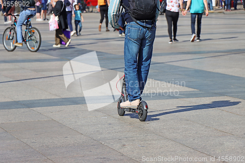 Image of Man riding a kick scooter at the city square