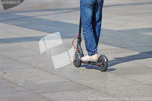 Image of Man riding a kick scooter at the city square