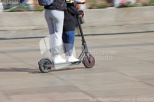 Image of Mother and son riding electric kick scooter at the city square