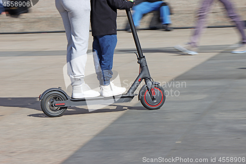 Image of Mother and son riding electric kick scooter at the city square