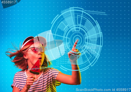 Image of Young caucasian woman\'s touching virtual reality in neon light