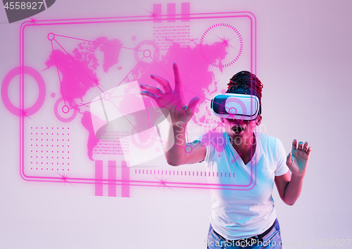 Image of Young african-american woman\'s using VR-glasses in neon light