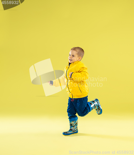 Image of A full length portrait of a bright fashionable boy in a raincoat