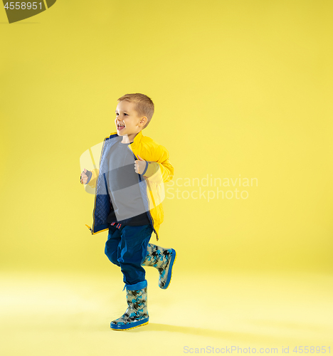 Image of A full length portrait of a bright fashionable boy in a raincoat