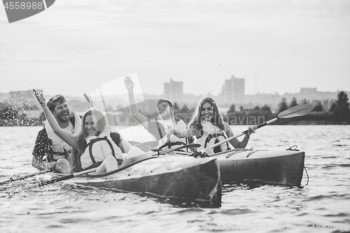 Image of Happy friends kayaking on river with sunset on the background