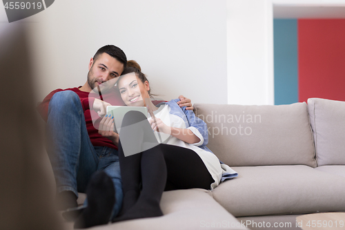 Image of couple relaxing at  home with tablet computers