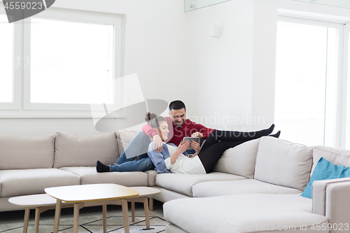 Image of couple relaxing at  home with tablet computers