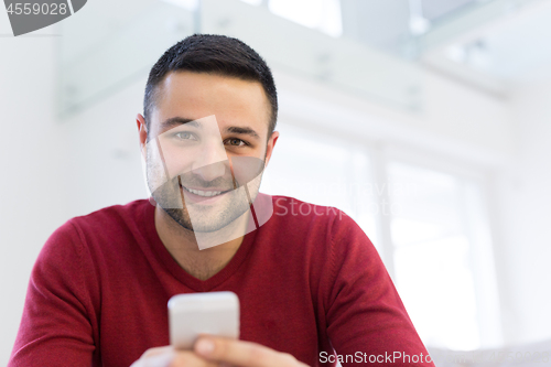 Image of young man using a mobile phone  at home