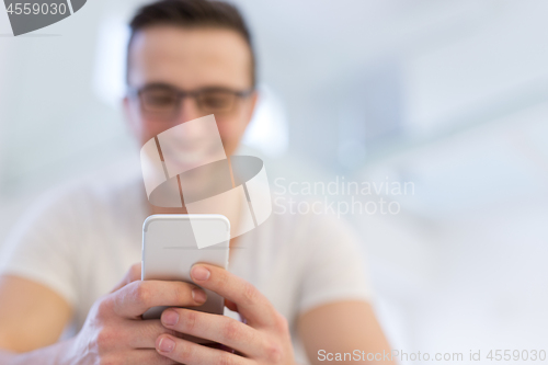 Image of young man using a mobile phone  at home