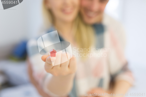 Image of couple showing small red house in hands