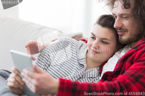 Image of couple relaxing at  home with tablet computers