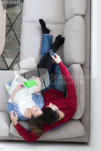 Image of Young couple on the sofa watching television top view