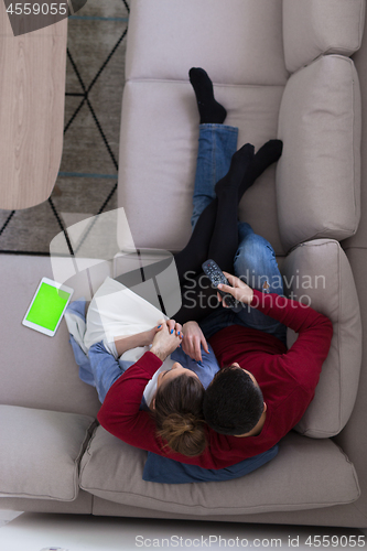 Image of Young couple on the sofa watching television top view