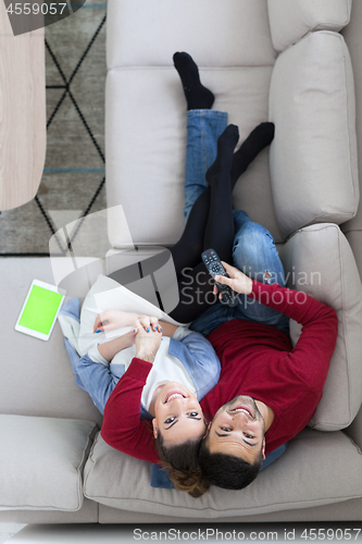 Image of Young couple on the sofa watching television top view