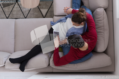 Image of couple relaxing at  home with tablet computers