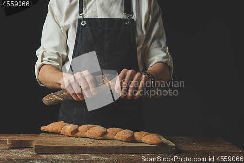 Image of Men\'s hands hold divided baguette halves