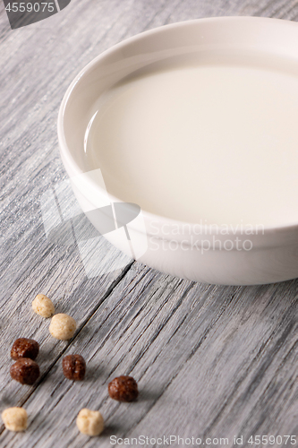 Image of White plate of milk and different cereal balls on a gray wooden table. Breakfast cereals