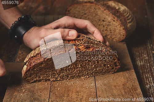 Image of Hands cutting rye bread